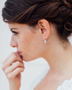 a woman wearing a wedding dress and earrings