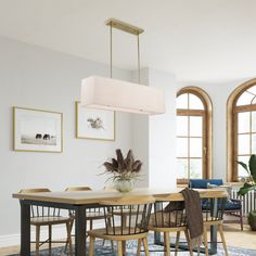 a dining room table with chairs and a potted plant in the center is surrounded by arched windows