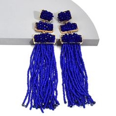 Doll up for your next night out with these dazzling resin tassel drop earrings! These earrings are the perfect accent for any outfit and will make everyone want a pair! With their unique shape and fun tassel detail, these stylish earrings will have heads turning wherever you Blue Tassel Drop Earrings, Blue Tassel Drop Earrings With Dangling Beads, Trendy Beaded Earrings For Party, Chic Party Beaded Drop Earrings, Chic Beaded Drop Earrings For Parties, Blue Fringe Tassel Drop Earrings, Elegant Blue Fringe Earrings, Tassel Chandelier Drop Earrings For Parties, Tasseled Chandelier Drop Earrings For Party