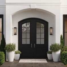 a black front door with two large white planters