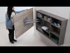 a woman is holding up a large book shelf with a sliding door on it's side