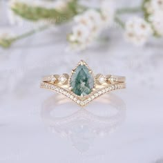 a close up of a ring with a green and white stone in it on a table