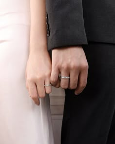 two people wearing wedding rings standing next to each other with their hands on the bride's lap