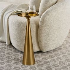 a gold candle holder sitting on the floor next to a white couch with a book