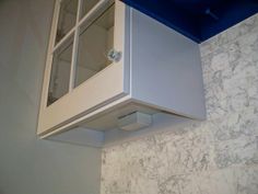 a white cabinet with glass doors on the wall next to a blue counter top in a kitchen