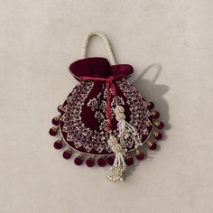 Introducing our exquisite Maroon Velvet Potli Bag - a perfect blend of sophistication and craftsmanship. This opulent bag is crafted from premium velvet fabric, ensuring a touch of luxury in every detail. Hand-embroidered with intricate patterns on one side, this potli bag radiates elegance. The beaded strap adds a glamorous touch, providing both comfort and style. Adorning the bag is a beautiful latkan featuring a beaded tassel, enhancing its charm. The meticulous embroidery work showcases the Festive Formal Shoulder Bag Pouch, Beaded Strap, Bridal Handbags, Ethnic Bag, Potli Bag, Wristlet Bag, Handmade Clutch, Potli Bags, Bridal Clutch