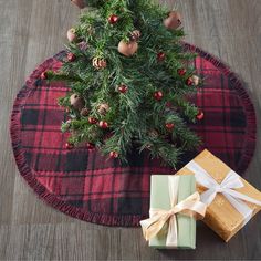 a christmas tree skirt with presents on it and a gift wrapped in ribbon next to it