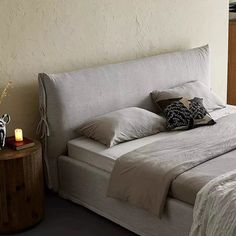 a bed with two pillows on it and a night stand in front of the bed