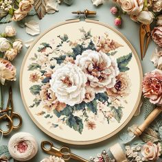 a cross stitch pattern with flowers and scissors on the table next to it is a bouquet of roses