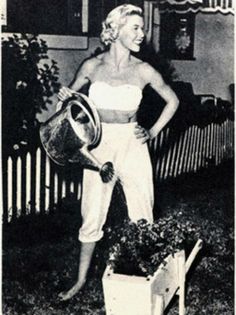 an old black and white photo of a woman holding a watering can