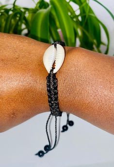 a close up of a person wearing a bracelet with a shell on it's wrist