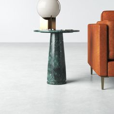 a chair and table with a lamp on it in front of an orange couches