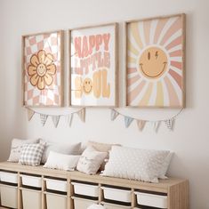 three framed pictures hang on the wall above a bench with pillows and storage bins