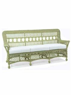 a green wicker couch with white cushions on it's back and armrests