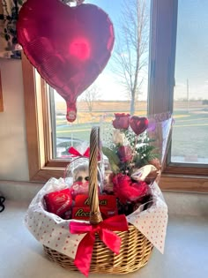 a basket filled with lots of valentine's day items in front of a window