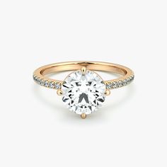 a gold engagement ring with a round cut diamond and pave set diamonds on the side