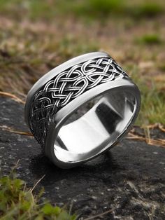 a silver ring sitting on top of a rock next to some green grass and dirt