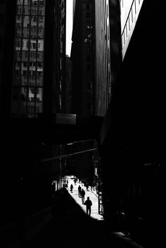 people are walking down the street in front of tall buildings with skyscrapers on either side