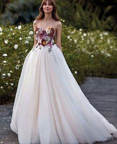 a woman in a white wedding dress standing on a sidewalk with flowers around her waist