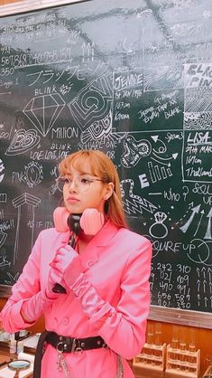 a woman holding a phone in front of a chalkboard