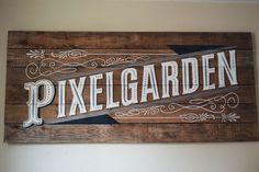 a wooden sign that says pixel garden on the side of a white wall