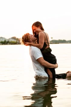 a man and woman are kissing in the water while holding each other's back