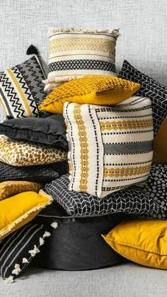 a pile of pillows sitting on top of a white bed covered in yellow and black