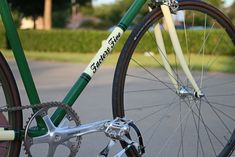 two green and white bicycles parked next to each other on the street with grass in the background