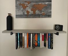 a book shelf with books and a clock on it in front of a white wall