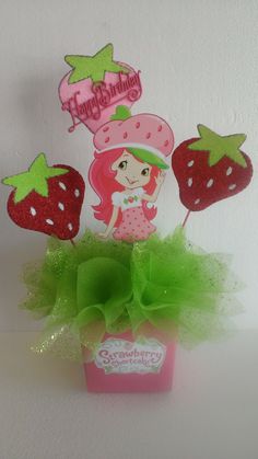 strawberry shortcake cake topper with green tulle skirt and strawberries on it