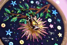 a close up of a sewing needle on a piece of cloth with fireworks and stars