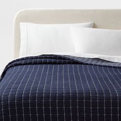 a bed with white pillows and blue checkered bedspread