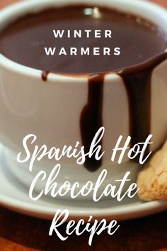 a cup of hot chocolate next to a biscuit on a plate with the words winter warmers spanish hot chocolate recipe