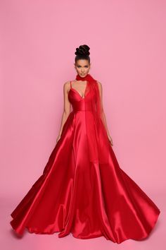 a woman in a red gown standing against a pink background