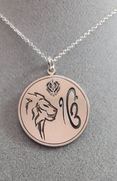 Are you looking for a special gift? How about this precious sterling silver pendant representing the Ik Onkar symbol, the Khanda sword, and the Lion? The Ik Onkar Symbol is the declaration of unity in Sikhism, that is 'there is only one God'. Ik Onkar are the first words of the Mul Mantar and also the opening words of the sacred Sikh scripture Guru Granth Sahib. The double-edged Khanda sword is a metaphor for Divine Knowledge, its sharp edges can separate truth from falsehood. Outside the circle Symbolic Coin-shaped Jewelry With Large Pendant, Symbolic Jewelry With Large Coin Pendant, Symbolic Large Coin Pendant Jewelry, Symbolic Engraved Round Pendant Jewelry, Traditional Pendant Jewelry For Commemoration, Symbolic Hallmarked Medallion Jewelry, Spiritual Sterling Silver Coin Jewelry, Silver Medallion Necklace In Symbolic Style, Symbolic Silver Coin Necklace