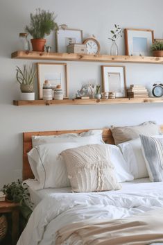 a bed with white sheets, pillows and pictures on the wall above it in a bedroom