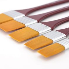 five paint brushes lined up in a row on a white surface with one yellow and the other red