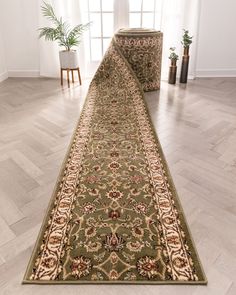 a long rug is on the floor in front of a window with potted plants