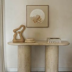 a table with two vases on it in front of a painting and some books