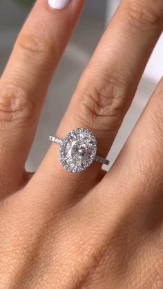 a woman's hand with a diamond ring on her finger and white nail polish