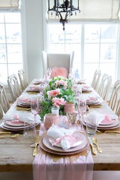 the table is set with pink and white plates, napkins, and place settings