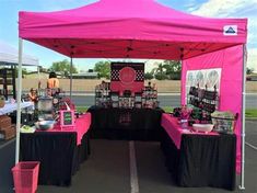 a pink tent is set up with black tablecloths and other items on it