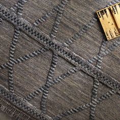 a piece of wood sitting on top of a gray and black rug next to a ruler