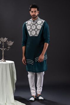 Peacock green sleeveless asymmetric bundi with bloom embroidery using pearls and beads. Paired with long sleeves plain kurta and matching churidar.
Components: 3
Pattern: Embroidered
Type Of Work: Pearl Bloom
Neckline: Band Collar
Sleeve Type: Bundi: Sleeveless, Kurta: Long
Fabric: Mal Cotton, Moss Crepe, Cotton Lycra
Color: Green
Other Details: 
Approx weight: 2kgs
Poly lining
Occasion: Mehendi and Puja, Sangeet - Aza Fashions Sleeveless Cutdana Kurta For Eid, Designer Sleeveless Bandhgala With Resham Embroidery, Designer Sleeveless Kurta For Navratri, Sleeveless Kurta With Chikankari Embroidery For Transitional Season, Designer Embroidered Green Nehru Jacket, Fitted Green Nehru Jacket With Dabka Detailing, Sleeveless Kurta With Intricate Embroidery For Diwali, Green Nehru Jacket With Intricate Embroidery For Designer Wear, Sleeveless Green Kurta For Wedding