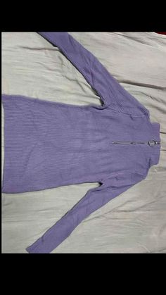 a woman's purple sweater laying on top of a bed