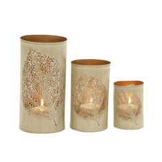 three vases with candles in them on a white background and one has a leaf design