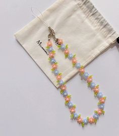 a pair of colorful beaded necklaces sitting on top of a white cloth bag