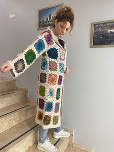 a woman standing on some steps wearing a crocheted coat