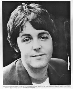 a black and white photo of a man in a suit with his hair pulled back