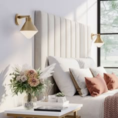 a bed with white sheets, pillows and flowers on the end table next to it